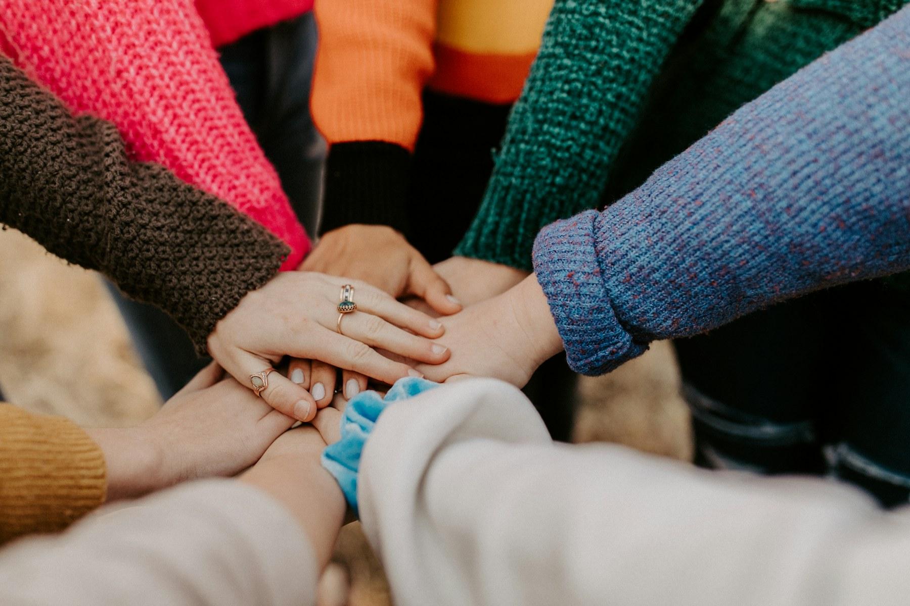 A group placing their hands together as a sign of shared community support